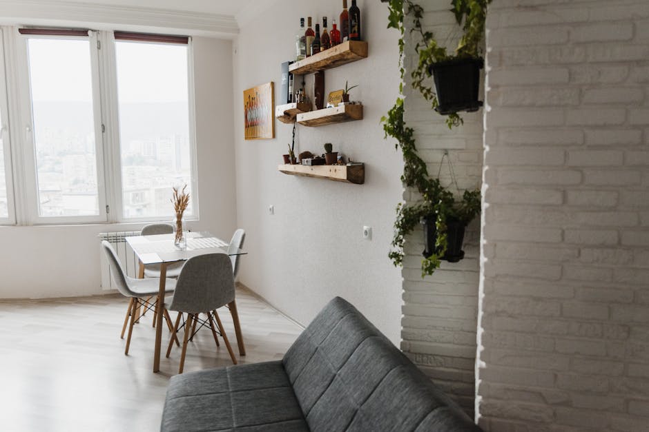 Bright and contemporary apartment interior with dining table, sofa, and decorative plants.